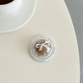 Macro view of clear spherical phone grip featuring a brown core and a white resin bow accent - Brown