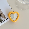 Detail of yellow heart-shaped phone grip with built-in mirror on a minimalist background - Yellow