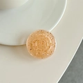 Detalle de soporte para móvil en resina ámbar con purpurina dorada sobre un plato minimalista - Naranja Ámbar