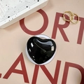 Detail of a glossy black heart phone socket stand on an artistic Port Land backdrop - Black