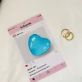 Macro di cuore in vetro blu con due anelli d'oro intrecciati su tessuto bianco - Blu lago