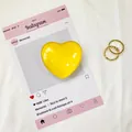 Vista ravvicinata di un supporto per telefono a cuore giallo lucido su sfondo in tessuto - Giallo