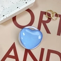 Close-up of a heart-shaped light blue glass phone stand with a transparent base on a desk - Sky Blue