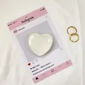 Dettaglio del supporto per telefono a cuore e gioielli d'oro su scheda estetica - Beige
