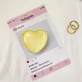 Dettaglio del supporto per telefono a cuore giallo traslucido su carta decorativa social - Giallo Chiaro
