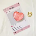 Dettaglio del supporto per telefono a cuore rosa lucido con eleganti anelli in metallo oro - Rosa Scuro Texturizzato