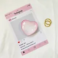 Vista dettagliata del supporto in cristallo rosa a cuore con anelli dorati su tessuto - Bordo Rosa Marmorizzato