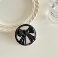 Detail der Magnet-Handyhalterung mit schwarzer Schleife und Good Luck Text auf Basis - Schwarz