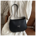 Detalle de bolso de hombro en cuero negro con un lazo metálico plateado sobre silla madera - Negro