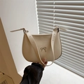 Beige matte leather underarm bag with silver metallic bow held against a white shutter - White