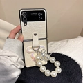 Close-up of cream leather phone case with large pearl ring and silver bow charm - White / Samsung ZFlip3