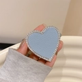 Detail of blue leather heart phone grip with silver rhinestones held by a hand - Light Blue