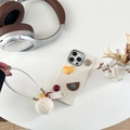 Dettaglio custodia iPhone in pelle crema con decoro 3D, cinturino intrecciato e pompon - Bianco Sporco / iPhone 7/8/SE 2020