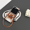 Detalle de funda Z Flip6 de tweed a cuadros con oso de peluche y cordón de cuero - Marrón / Samsung ZFlip3