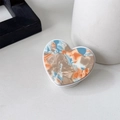 Close-up of heart-shaped phone grip with blue and orange marble texture on white desk - Orange Blue