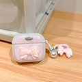 Detalle de funda AirPods con purpurina rosa, lazo 3D y colgante de perlas sobre madera - Lazo de Purpurina Rosa Mágico / AirPods 1.ª/2.ª generación