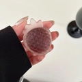Macro detail of the semi-transparent pink strawberry resin phone grip with matte finish texture - Brown