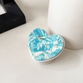 Detail of heart-shaped phone grip with blue marble texture on minimalist white desk - Blue