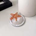 Detail of orange starfish phone grip with gold glitter and white pearl on gift card - Magnetic Round Pearlescent Starfish / Brown