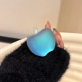 Detail of an iridescent apple phone grip with rainbow gradient finish in hand - Dazzling Light Blue