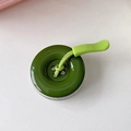 Dettaglio di un supporto per telefono a forma di bottone verde bosco con laccetto intrecciato - Verde Scuro