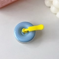 Dettaglio del supporto per telefono a bottone blu con cordino giallo e base chiara - Azzurro