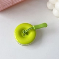 Dettaglio del supporto per telefono a forma di bottone verde con cinturino intrecciato - verde chiaro