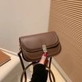 Brown vintage leather crossbody bag with golden buckle shown held in hand for size comparison - Brown