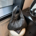 Minimalist charcoal hobo tote bag with vertical stitched panels on a white stool - Black