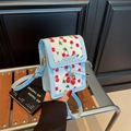Blue square crossbody bag with red cherry prints and decorative pendant on a chair - Cherry Blue