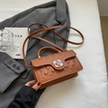 Brown quilted handbag with floral clasp and wavy edges on a stylish blazer background - Brown