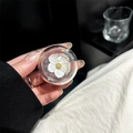 Macro shot of a clear resin phone grip featuring a white floral motif with gold accents - Adhesive Round Faux Shell Flower