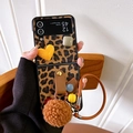 Detail of leopard print phone case with brown plush ball and stylish wrist strap - Leopard Geometric Yellow Heart Fur Ball / Samsung ZFlip3