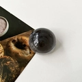 Detail of a polished black crystal ball phone grip with a smooth reflective finish - Transparent Black