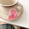 Detailed view of an iridescent pink bow phone socket on a white coffee saucer - Iridescent Bow - Pearlescent Rose Red