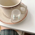 Schillernde Schleife Handy-Halterung aus Harz mit Perlmutt-Effekt neben einer Kaffeetasse - Irisierende Schleife - Perlmuttweiß