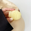Detail shot of cute yellow taiyaki fish phone socket grip held by a hand on a beige hat - Matte Light Jelly Yellow