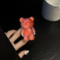 Vista macro di un supporto per telefono a forma di orsetto 3D con sfumatura laser arancione - Rosso Abbagliante
