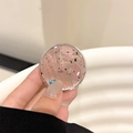 Detailed close-up of a pink resin phone grip featuring shimmering gold foil and black flakes - Brown