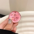 Close-up of pink translucent phone grip with embedded red gold foil glitter detail - Red