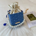 Dettaglio della borsa a secchiello in denim con manico di perle e sacchetto interno beige - Blu
