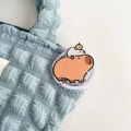 Cute cartoon Capybara acrylic phone socket grip attached to a light blue quilted bag - Capybara Picking Oranges (No. 11)