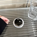 Detail of round black magnetic phone grip with gold rimmed crystals on clear gift packaging - Black Metal Dandelion Magnetic Style