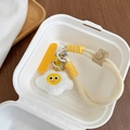 Close-up of plush poached egg phone strap with thick braided rope and yellow letter F charm. - Fried Egg Style / Off-white Braided Rope
