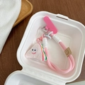 Close-up of pink braided phone lanyard with cute plush smiley sandwich charm in box - Rice Ball Style / Pink Braided Rope