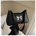 Détail d'un sac selle en similicuir noir avec un nœud métallique argenté et une bandoulière - Noir