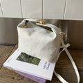 Primer plano de un bolso bandolera blanco texturizado con elegantes detalles dorados - Blanco