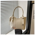 Detail showing creamy white pebbled leather texture and gold hardware on the handbag - White