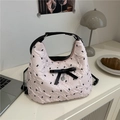Chic pink quilted handbag with black bow and heart pendant on white minimalist desk - Pink