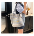 Detail shot of striped canvas tote bag with oval metal logo and plush white doll charm - With Plush Charm / Black